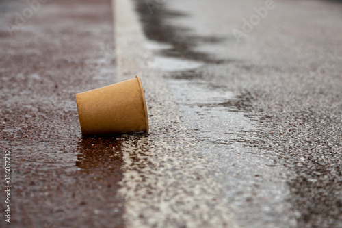 Kyiv, Ukraine - March, 22, 2020: Used paper cup on a wet road.