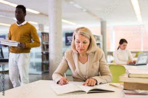 Woman with books sits at table in the library