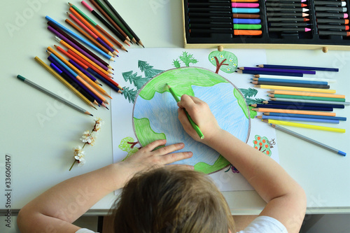 Fototapeta Naklejka Na Ścianę i Meble -  Child girl draws planet for earth day. Protection of enviroment, Save our planet. Concept of art learning and education, love earth , save world and unity.Ecology concept
