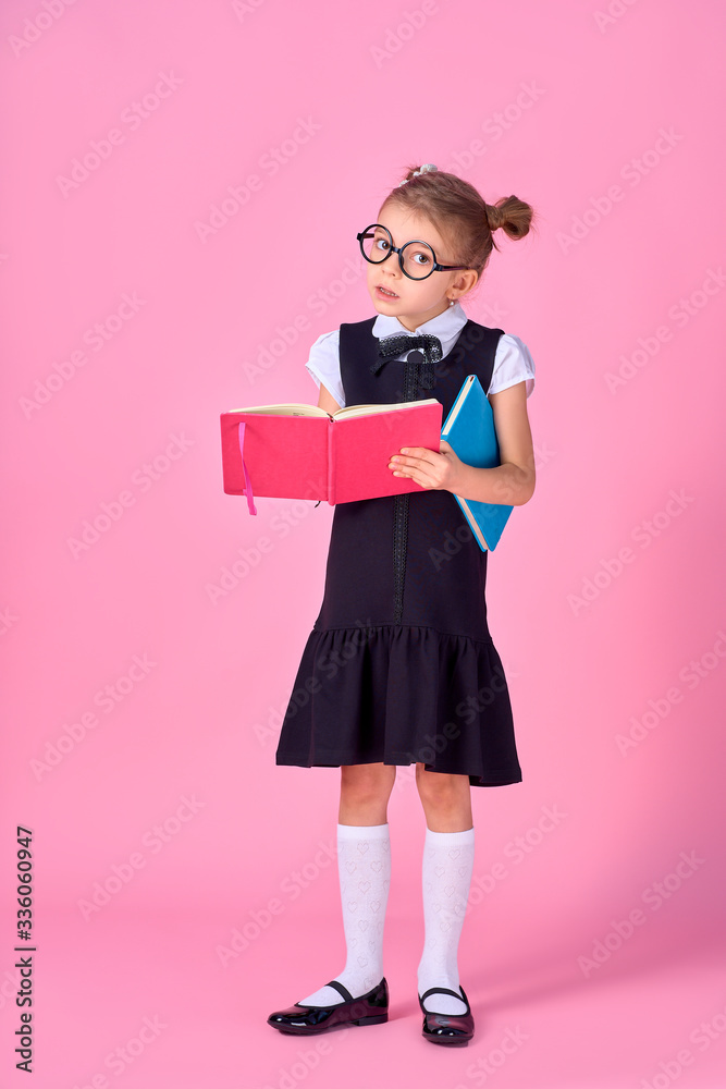 Cute little girl with glasses and books on pink background, space for text. Reading concept. Cute little girl with glasses and books on pink background, space for text. Reading concept.