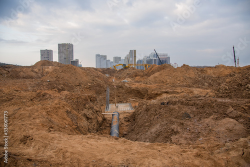 Excavator at construction site during laying sewer and main reticulation systems. Civil infrastructure pipe, water lines, sanitary sewers and storm sewers. Underground utilities installation