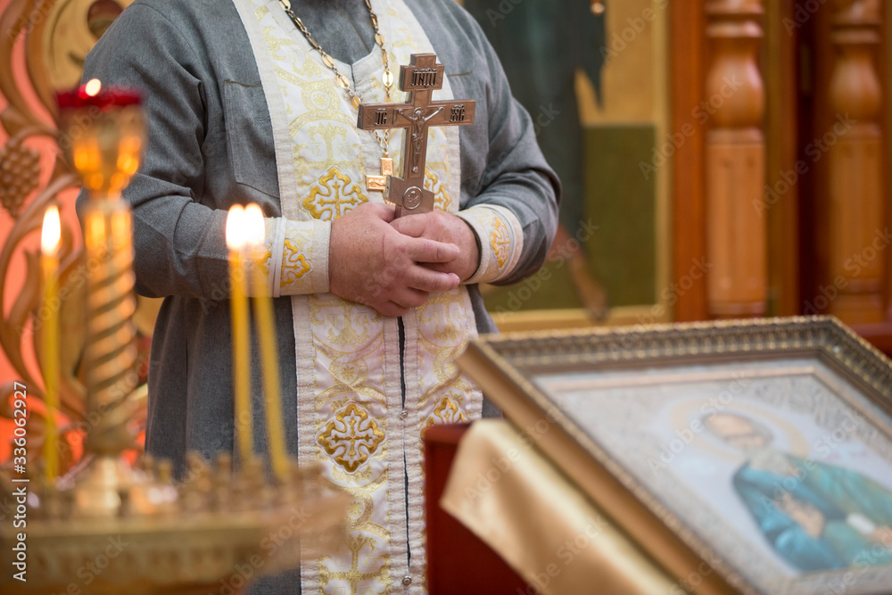 Obraz premium Priest with a cross on the background of the icon.
