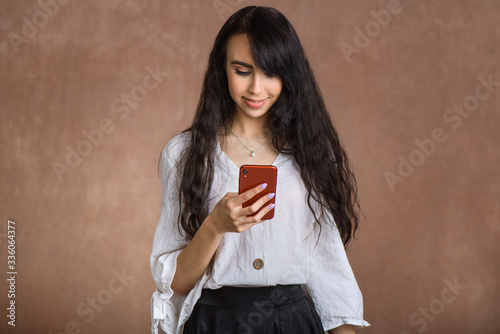  Satisfied girl types text message on cell phone, enjoys online communication