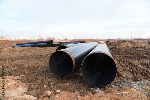 Sections of pipe on top of wooden supports at an construction site for natural gas. Construction of gas pipeline to new LNG plant. Excavated trench to install gas supply pipework for the power station