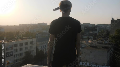 A young guy, a scion on the roof of a Soviet house. Sunset. Slow motion.
