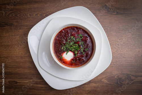 Red borscht soup with dill in white bowl.