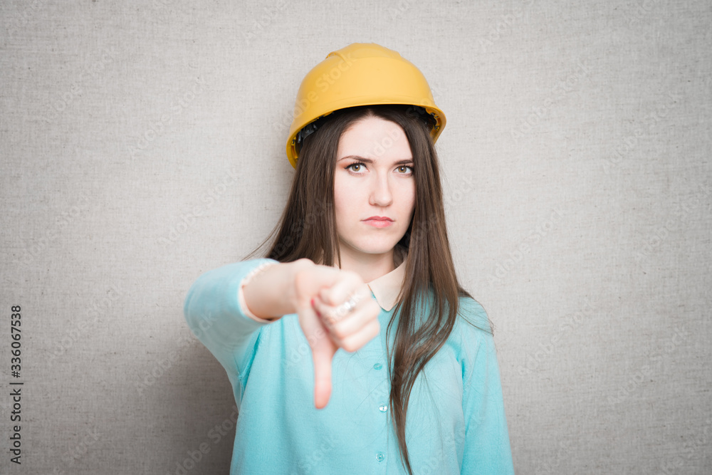 woman with thumb down gesture helmet. isolated on gray background