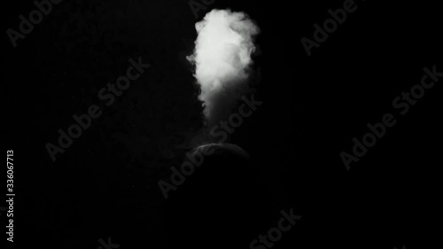 the silhouette of a man on a dark background exhales clouds of smoke