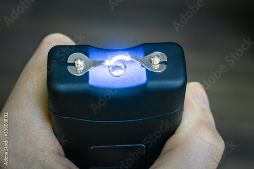 Personal taser for protection against bandits is in the hands. The use of a stun gun with a powerful electric discharge. Turning on the device for self-defense. Action of the stun gun is close-up. 