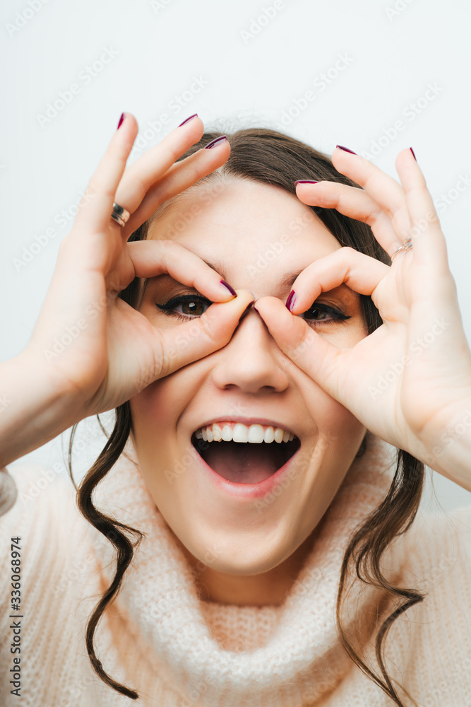 Portrait of pretty young woman looking through hole from fingers. Portrait of pretty young woman looking through hole from fingers.