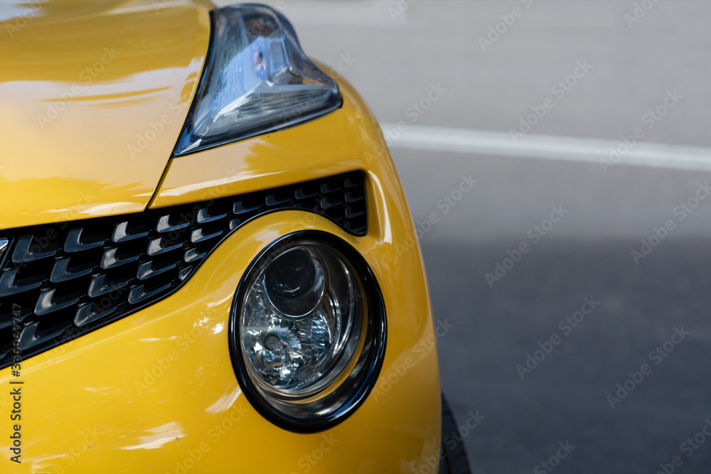 Clean headlights of yellow car. Close-up of the front left headlight.