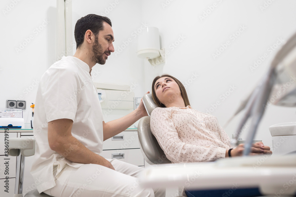 Portrait of a bearded dentist male explaining procedure to a female patient