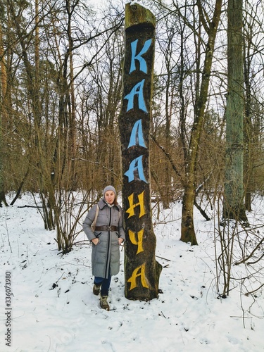 woman near Kalancha wooden post in snowy forest photo