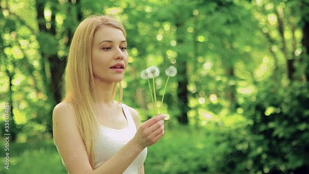 Blond girl blowing on dandelions in the park. Blond girl blowing on dandelions in the park.