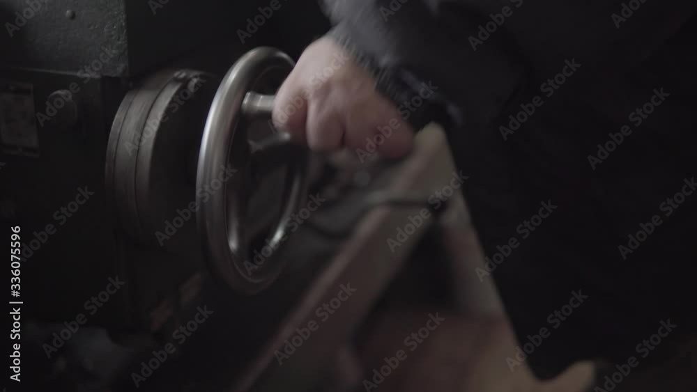 Old worker quickly rotates the crank of a metal lathe machine Old worker quickly rotates the crank of a metal lathe machine
