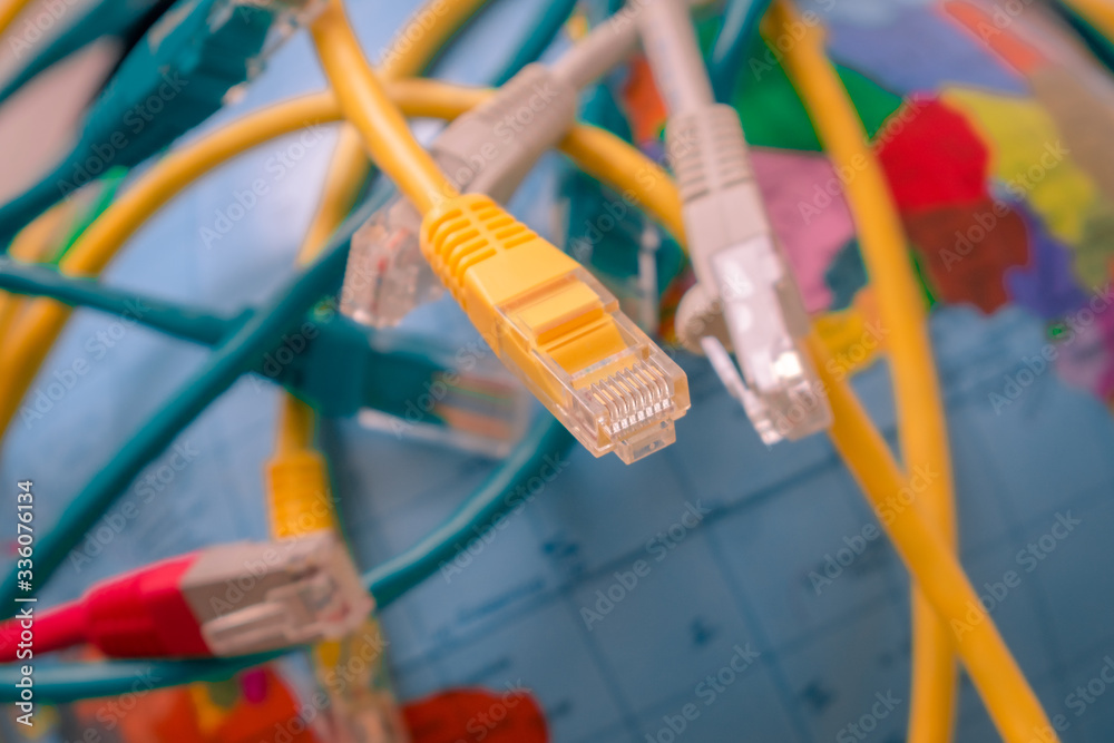 Background from connecting server patch cords. Terminal end is a close-up. A lot of tangled internet wires entangle around the globe. A messy cable plexus is on the world map.