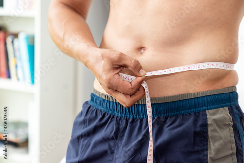 Muscular male man torso with measuring tape, weight loss and dieting concept photo