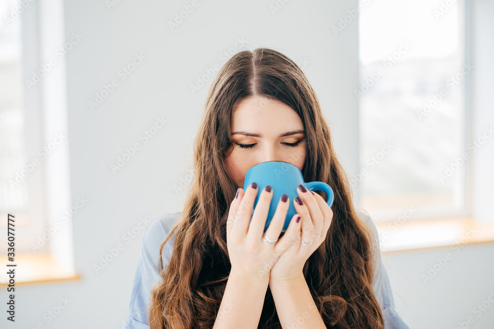 Portrait of a young woman near the window with cup of tea