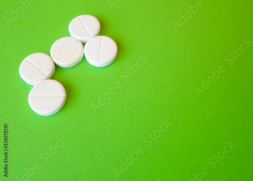 white pills on a green background. snow-white round antibiotics against viruses photo