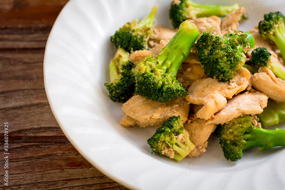 Top view stir fried broccoli and chicken in white plate on wooden table. Top view stir fried broccoli and chicken in white plate on wooden table.