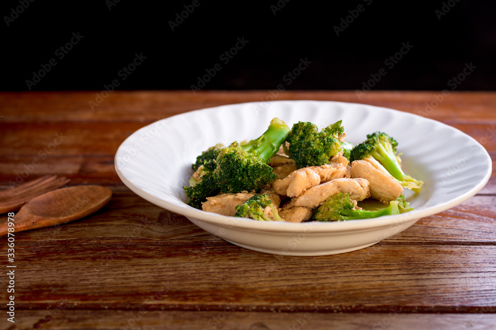 Stir fried broccoli and chicken in white plate on wooden table. Stir fried broccoli and chicken in white plate on wooden table.