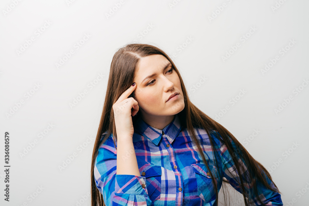 young woman thinks his finger to his temple young woman thinks his finger to his temple