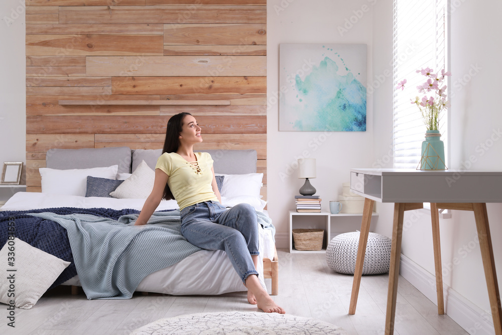 Obraz premium Woman sitting on bed in modern room. Elegant interior