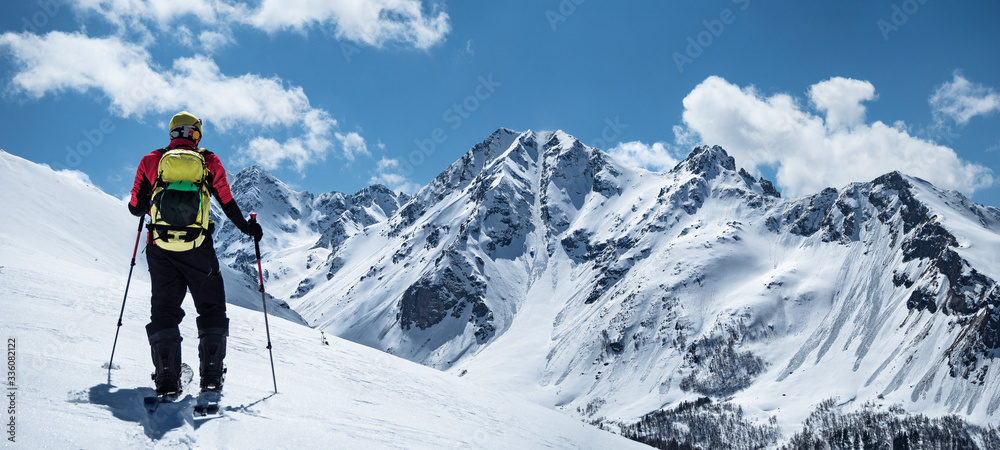 Back view of active man ski touring at mountains background at sunny winter day Back view of active man ski touring at mountains background at sunny winter day