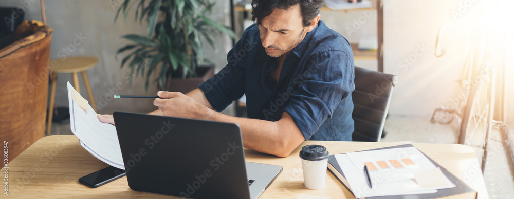 Man working on laptop at bright studio - obrazy, fototapety, plakaty 