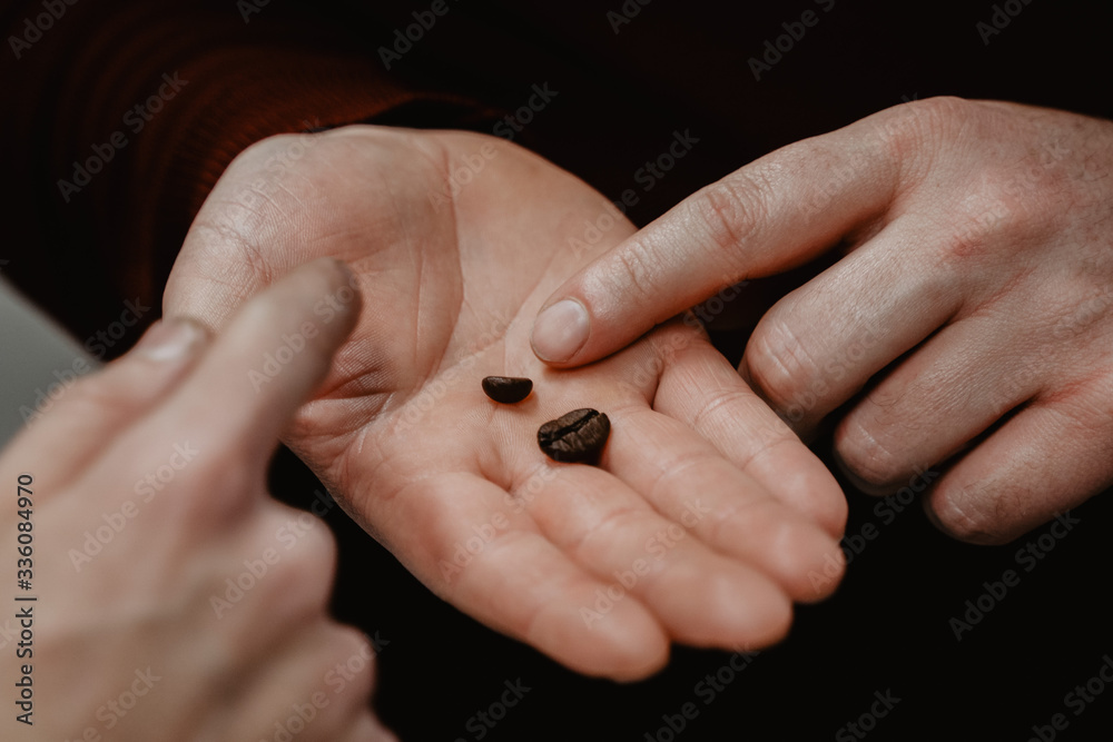 manos de hombre señalando granos tostados de café arábica