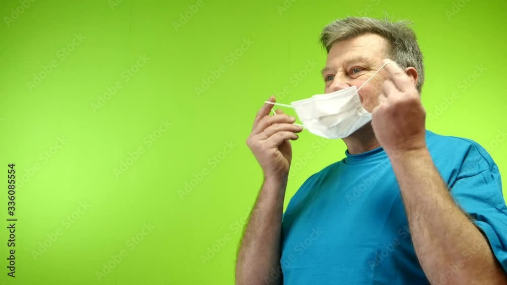 Positive senior adult man takes off his protective medical mask which coronavirus protection outside and wink. Optimism and love of life. Green background. Chromakey. Close-up. Positive senior adult man takes off his protective medical mask which coronavirus protection outside and wink. Optimism and love of life. Green background. Chromakey. Close-up.