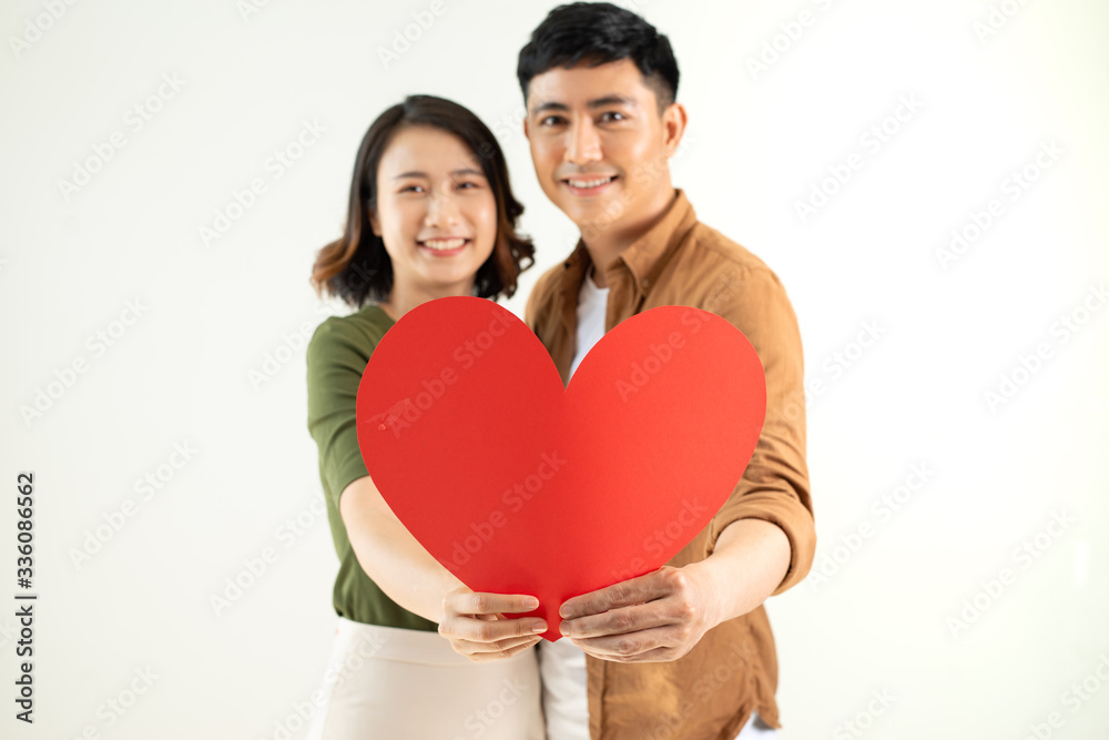 Happy young Asian couple holding heart shape over white background.