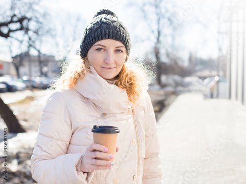 Woman holding brown paper coffee cup outdoor. Template mock up, pink manicure, sunny winter day