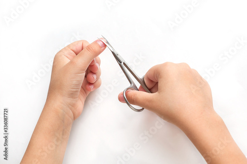 A child cuts his fingernails with manicure scissors at home. On a white background. Quarantine  isolation  independent activity. quarantine  isolation  independent activity