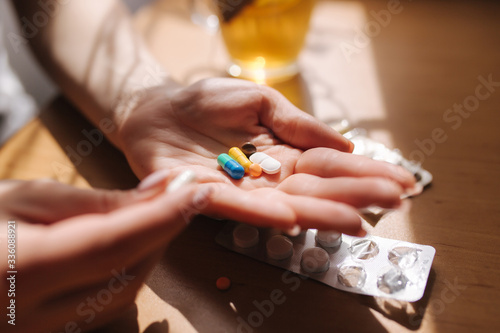 Close up of woman's hands hold pills. Hand with pills and black tea with lemon. Immunity. Vitamines