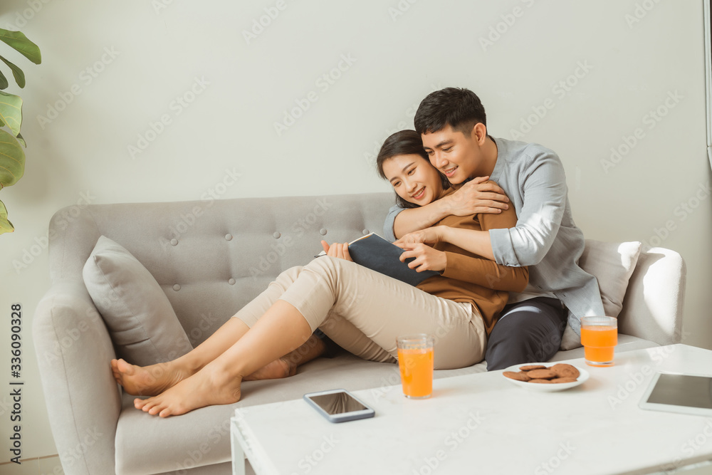 Portrait of young couple reading book sitting on couch