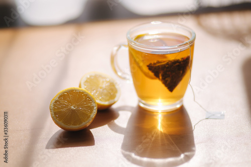 Black tea with lemon on wooden table. Tea bag with lemon slice in cup