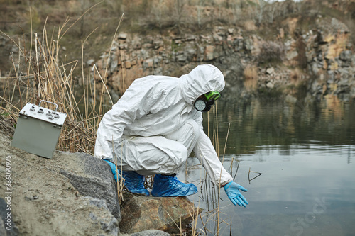 Girl in protective overalls on the nature. Biological protection suit. Personal protective equipment to prevent transmission of the virus. The concept of coronavirus, pandemic, flu and quarantine.