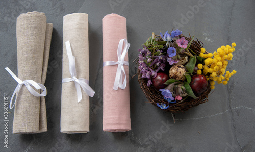 Easter composition with a nest of quail eggs and linen napkins, rolled and tied with ribbons.