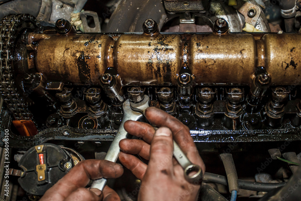 Car engine without valve cover. The mechanic is setting up the valve