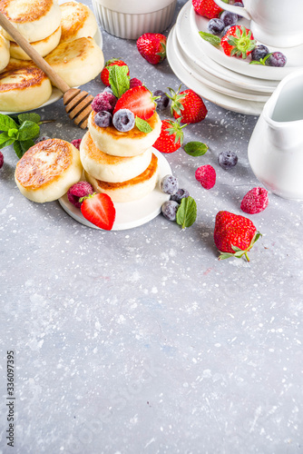 Cottage cheese pancakes with honey and various summer berry on grey background, summer breakfast or lunch