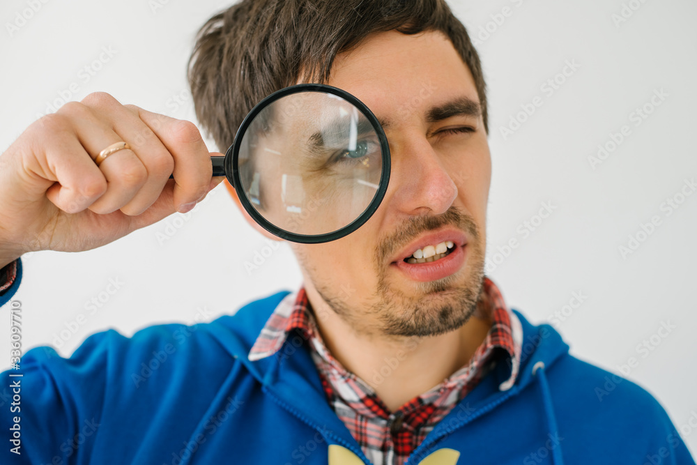 on a gray background young man with a magnifying glass on a gray background young man with a magnifying glass