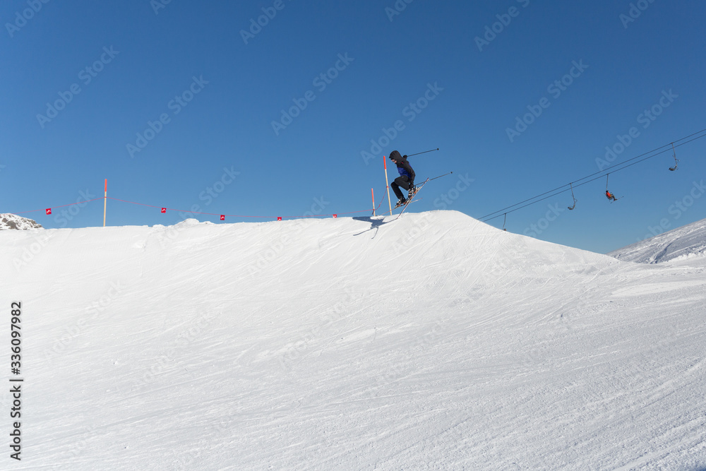young skier is jumping over a little snow hill 
