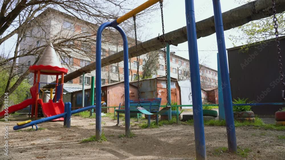 Lonely blue swings swing in an empty children playground in the center