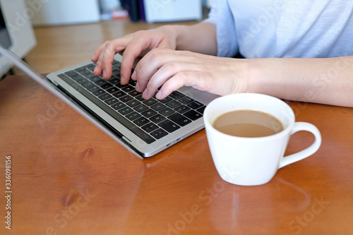 Closeup of hands of a woman typing on a laptop at home