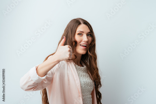 on a gray background young girl showing thumbs up