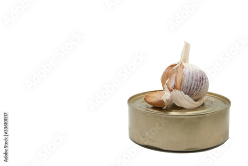 A head of garlic lies on a tin can. The picture is isolated on a white background.
