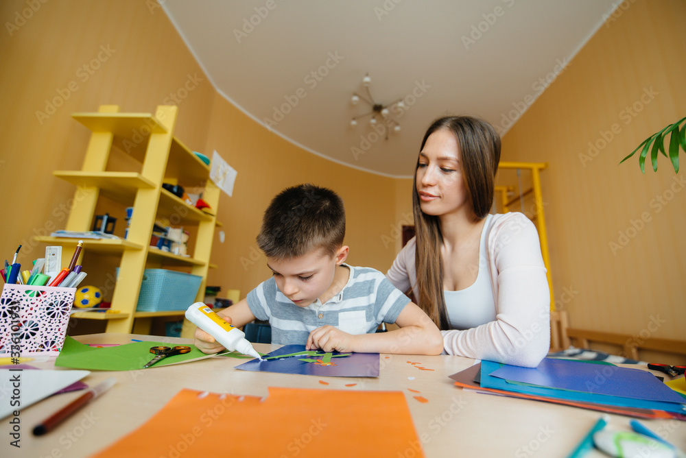 A young mother is doing homework with her son at home. Parents and training