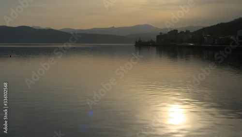 水面に反射する太陽と街並み © hoshi