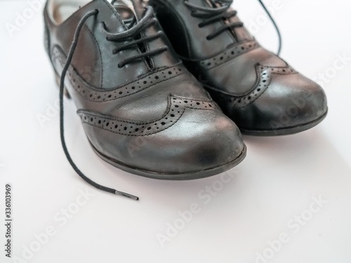 Front on view of a ladies pair of classic black leather heeled brogues with close up and selective focus on a plain white background